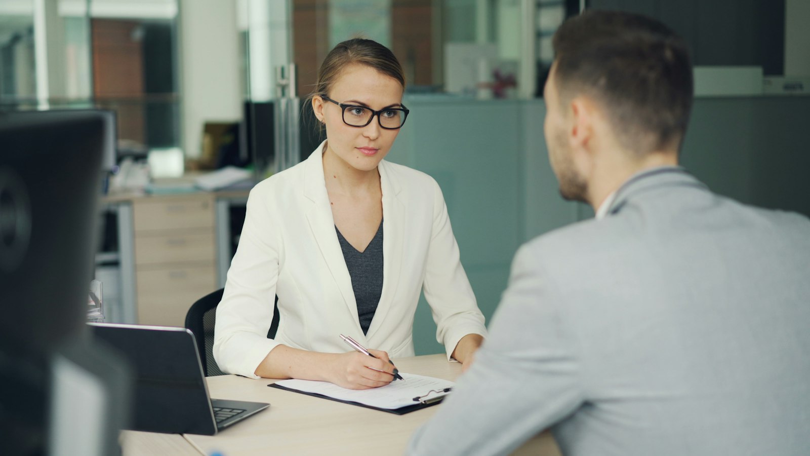 Recruiter in gesprek met een kandidaat aan een bureau, beeld voor AI in recruitment en het menselijke gesprek